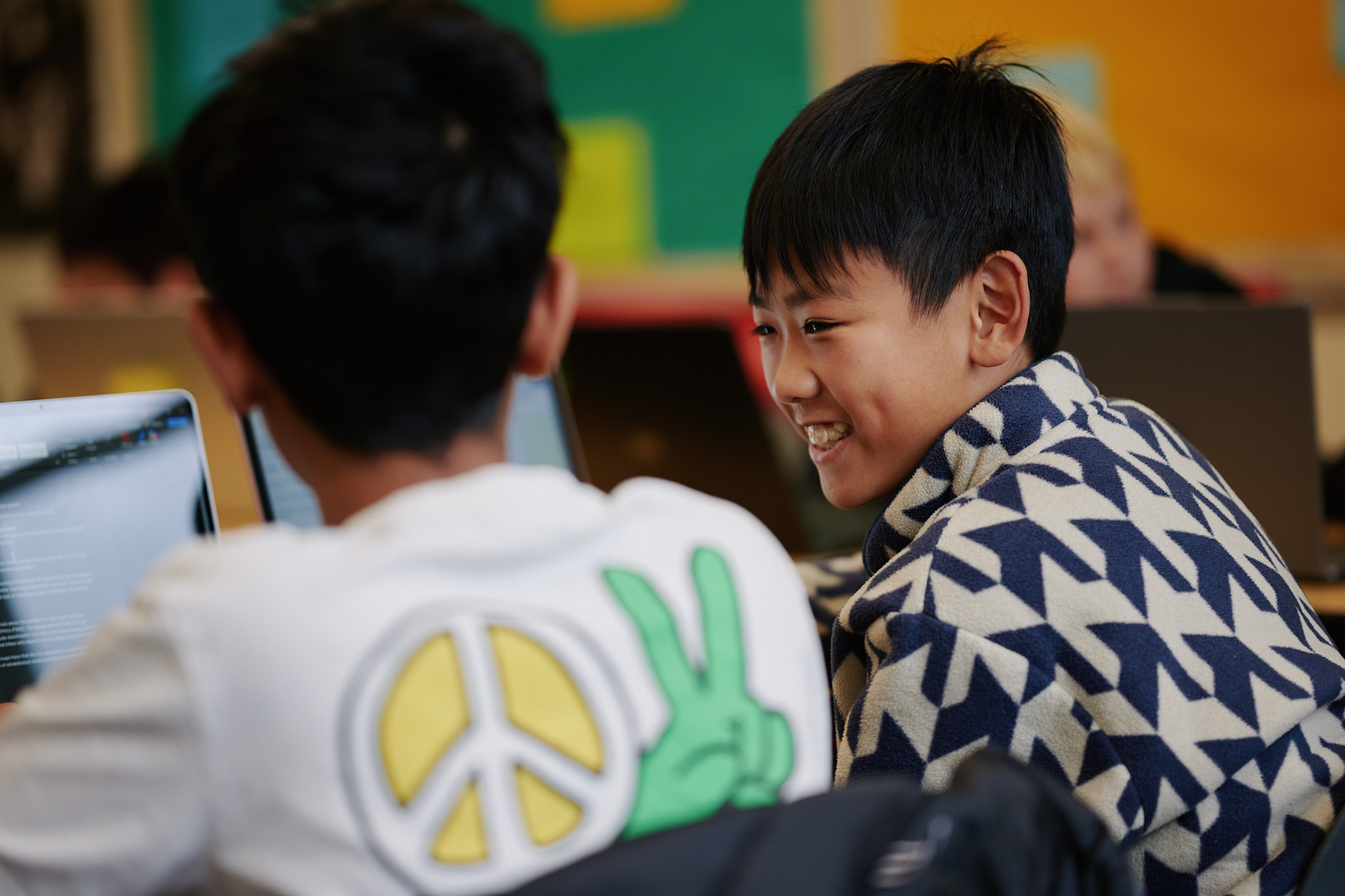 student at desk smiling from behind