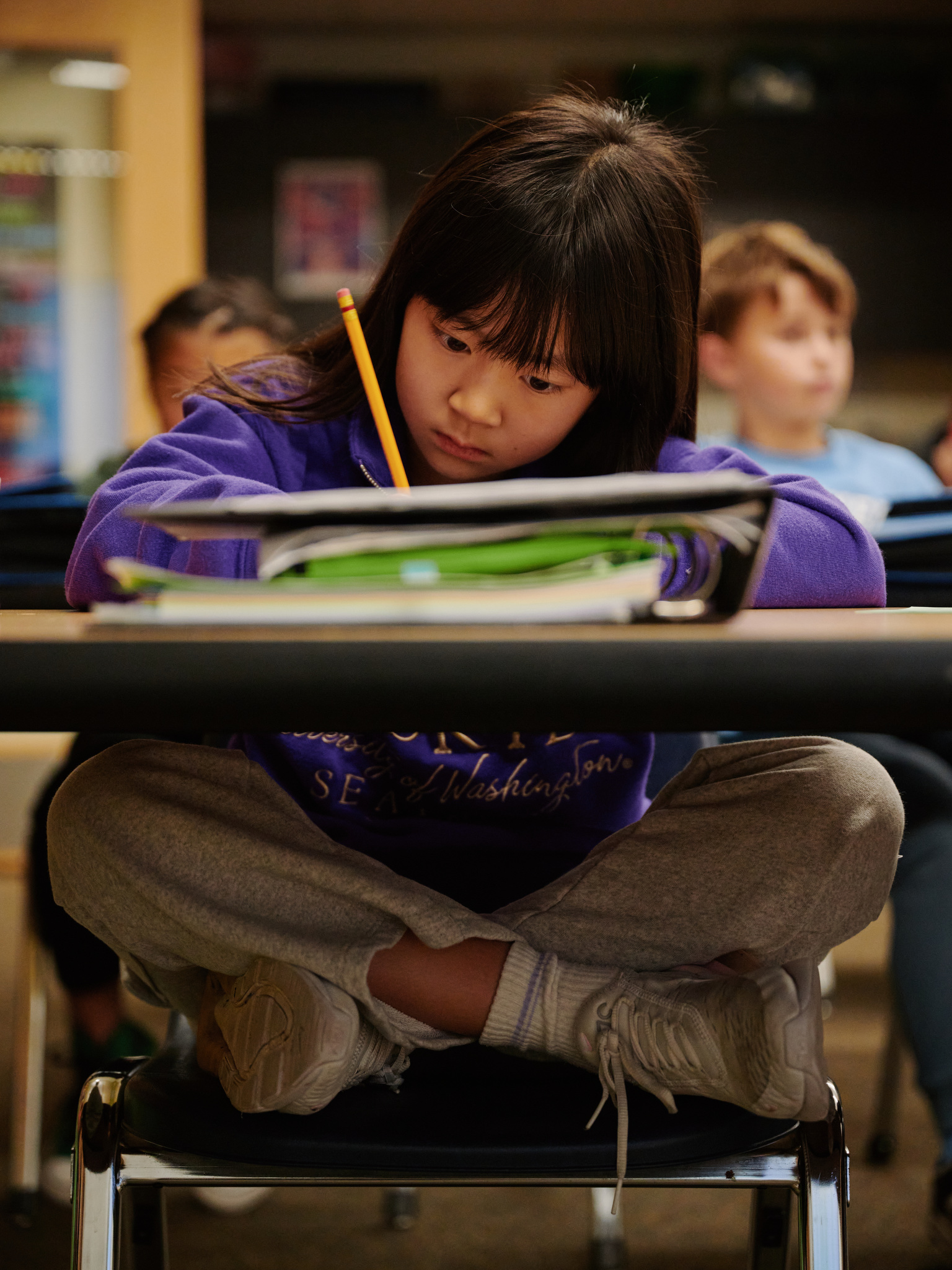 close up of middle school student writing in notebook at desk