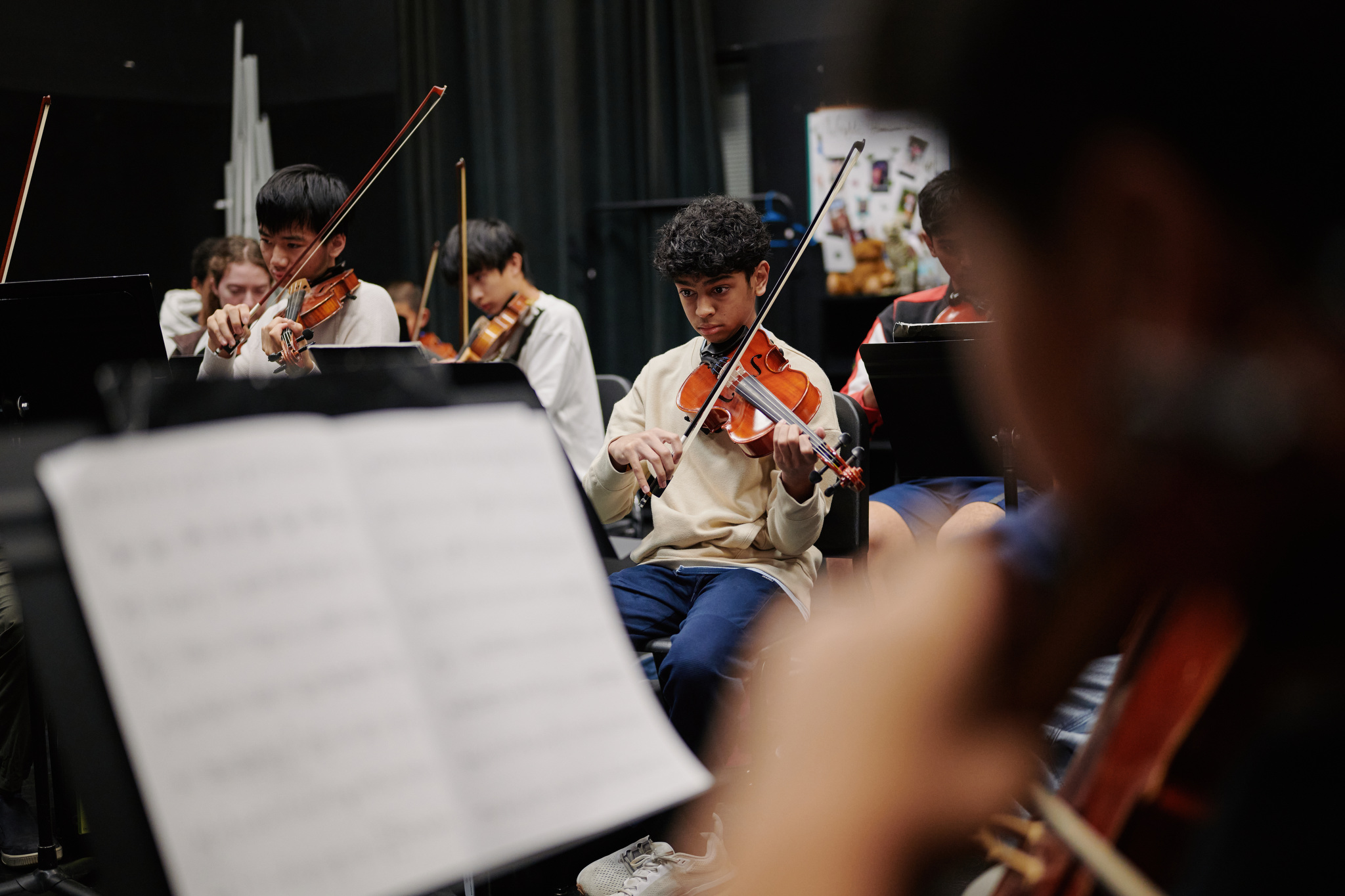 three violin players with sheet music in foreground
