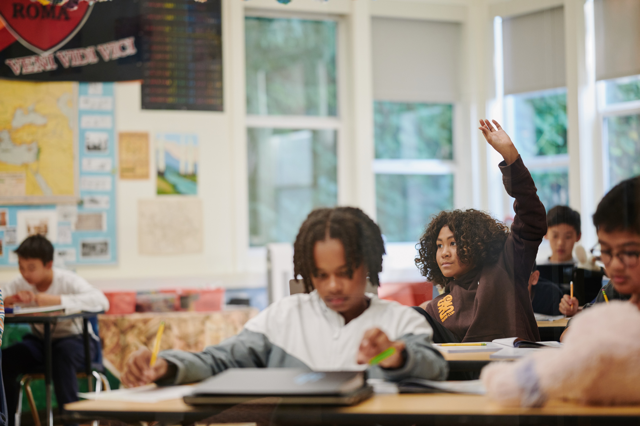 middle school student with hand raised in class