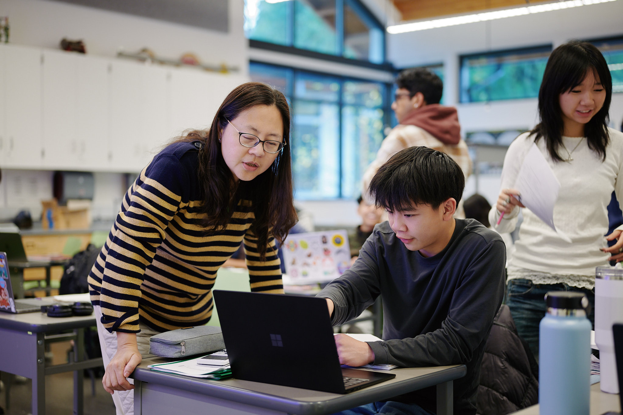 teacher helping student at desk