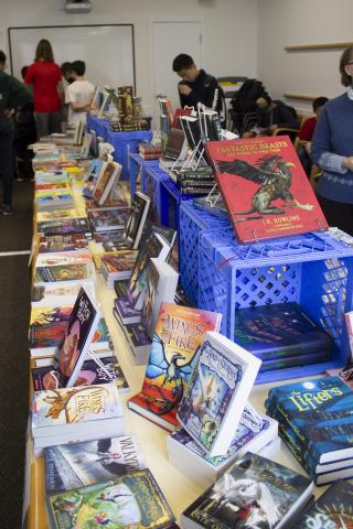 Table covered with new books and students browsing