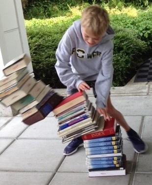 Boy tipping over stack of books