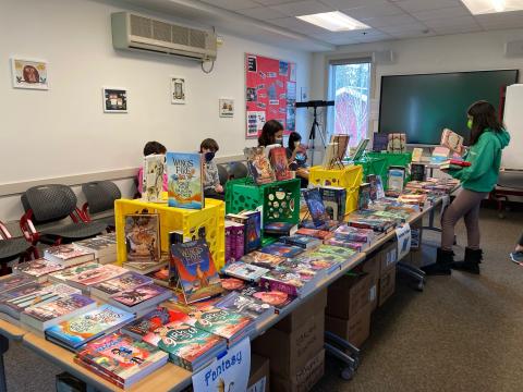 Table covered with books and students perusing them