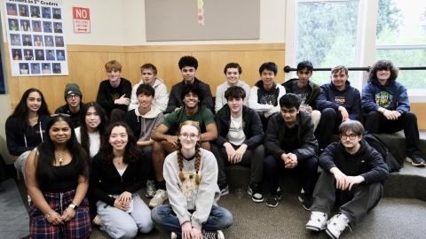 19 senior Lifers sit facing the camera and smiling in the 5/6 amphitheater.