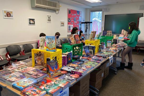 Table covered with books and students perusing them