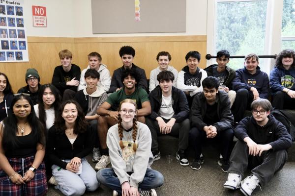 19 senior Lifers sit facing the camera and smiling in the 5/6 amphitheater.